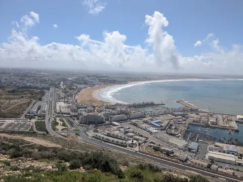 Agadir’s curved sandy bay, marina and white city buildings seen from the hill of Agadir Oufella.