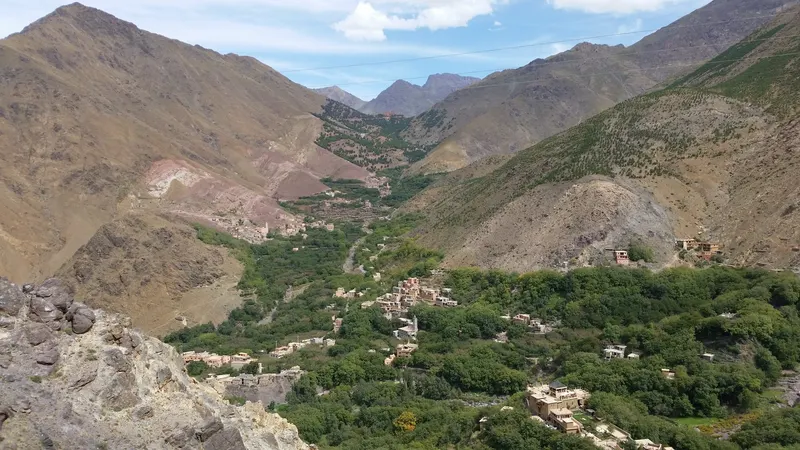 Village buildings and green trees fill the Imlil valley between steep, brown mountain slopes.