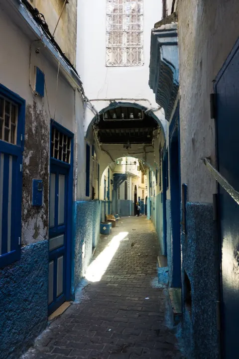 A narrow covered passage with blue-painted doorways in the Tangier medina.